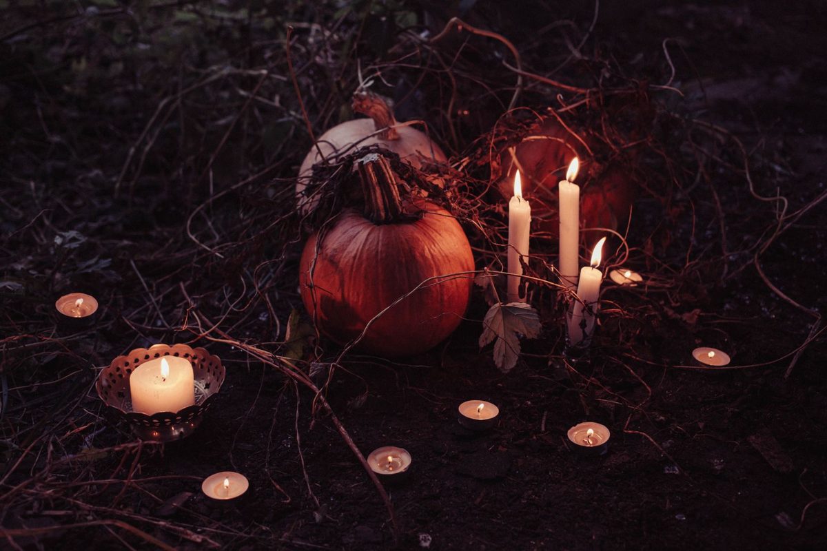 Κολοκύθα Halloween ανάμεσα σε αναμμένα κεριά και ρεσό